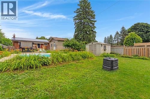 Expansive backyard featuring a central lawn area, an in-ground swimming pool, mature perimeter trees, and a detached storage shed - 744 Birchwood Avenue, Cambridge, ON - Outdoor