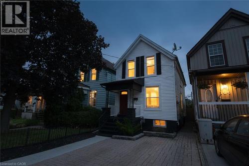 White siding exterior with black shutters, a covered entry, and a paver driveway - 106 Belview Avenue, Hamilton, ON - Outdoor With Facade