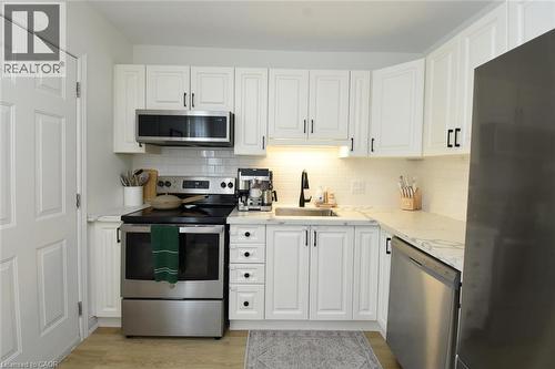 Contemporary kitchen featuring white cabinetry, stainless steel appliances, a subway tile backsplash, and light-toned countertops - 106 Belview Avenue, Hamilton, ON - Indoor Photo Showing Kitchen With Stainless Steel Kitchen With Upgraded Kitchen