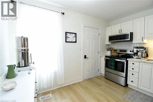 Bright kitchen featuring white cabinetry, light wood-finish flooring, a stainless steel range, and a white subway tile backsplash - 106 Belview Avenue, Hamilton, ON - Indoor Photo Showing Kitchen