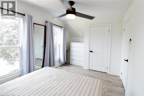 Bright interior space featuring two windows with white trim, a ceiling fan with integrated lighting, and light wood-finish flooring - 106 Belview Avenue, Hamilton, ON - Indoor Photo Showing Bedroom