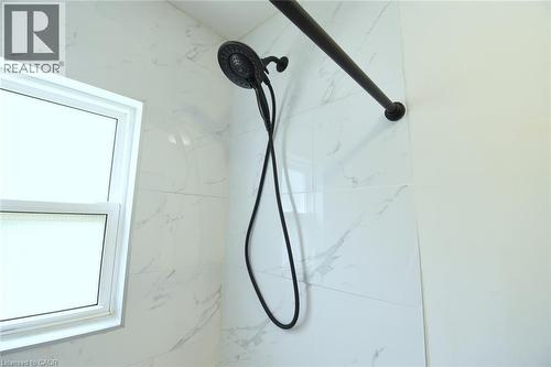 Shower enclosure featuring white marble-look wall tiling and a matte black shower head with an integrated handheld sprayer - 106 Belview Avenue, Hamilton, ON -  Photo Showing Bathroom