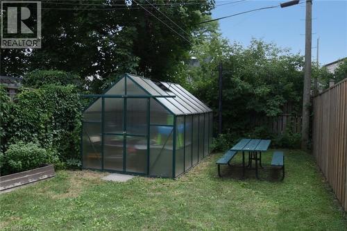 Rear yard featuring a freestanding greenhouse, a picnic table, and perimeter fencing - 106 Belview Avenue, Hamilton, ON - Outdoor