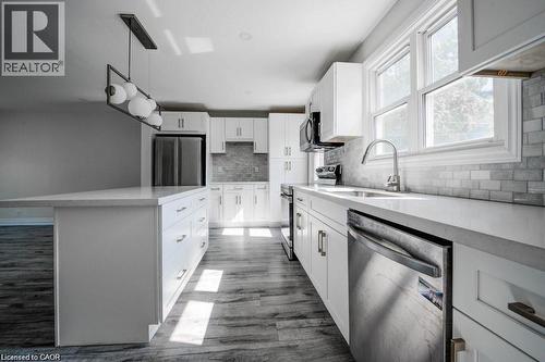 Kitchen featuring an oversized island with a white countertop, white shaker-style cabinetry with brushed nickel hardware, and wood-finish flooring - 33 Sixth Avenue Unit# Upper, Kitchener, ON - Indoor Photo Showing Kitchen With Upgraded Kitchen