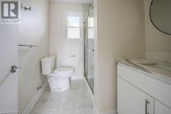Bathroom featuring a glass-enclosed shower, white vanity with an integrated sink and stone countertop, and large format tile flooring - 
