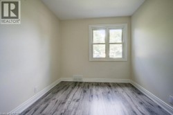 Room featuring wood-finish flooring, light-toned walls, and a white-framed window - 
