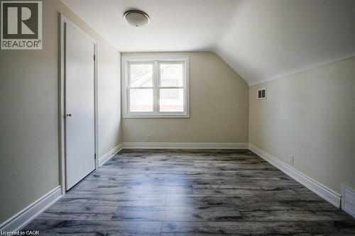 Attic room featuring wood-finish flooring, white trim, a double-hung window, a single door, and a flush-mount ceiling light - 33 Sixth Avenue Unit# Upper, Kitchener, ON - Indoor Photo Showing Other Room