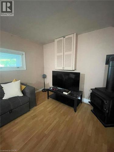 Living area featuring wood-finish flooring, a wall-mounted louvered cabinet, and a window with natural light - 267 Mackie Place Unit# 2, Kitchener, ON - Indoor Photo Showing Other Room