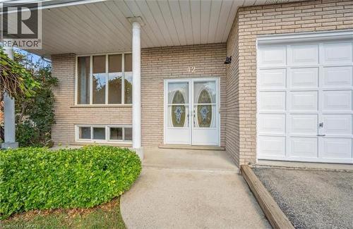 Brick exterior featuring a covered entry porch supported by white columns, double front doors with decorative glass inserts, a single-car garage with a panelled door, and a concrete pathway with manic - 42 Azores Crescent, Cambridge, ON - Outdoor With Exterior