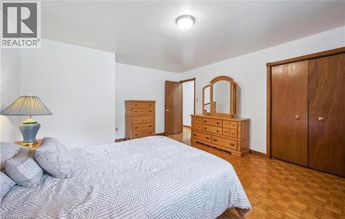 Bedroom featuring parquet wood-finish flooring, white painted walls, a flush-mount ceiling light, and a brown wood-finish bi-fold closet - 42 Azores Crescent, Cambridge, ON - Indoor Photo Showing Bedroom