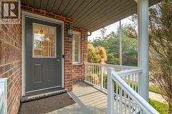 Covered front porch featuring a brick facade and a dark gray entry door with windowpanes - 