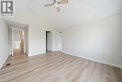 Spacious room featuring wood-finish flooring, vaulted ceilings, and a ceiling fan - 