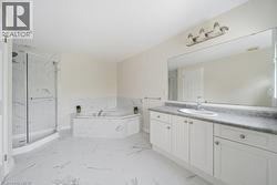 Bathroom featuring a corner soaking tub, a separate glass-enclosed shower, a double vanity with a single basin, a large wall-mounted mirror, and tile flooring - 