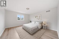 Spacious room featuring wood-finish flooring, white baseboards, and a large window providing natural light - 