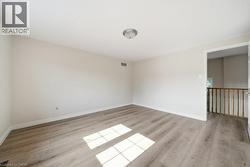 Spacious room featuring light-toned wood-finish flooring, neutral wall paint, and white trim - 