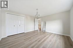 Spacious room with light wood-finish flooring, white baseboards, and neutral wall tones - 