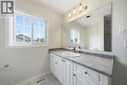 Bathroom vanity featuring white shaker-style cabinetry with chrome hardware, an integrated sink, and a large wall-mounted mirror - 