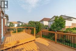 Spacious outdoor deck featuring natural wood-finish planks, dark balusters, and a matching wood-finish railing - 