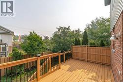 Spacious outdoor deck featuring wood-finish flooring, a wood railing with black balusters, and integrated post-cap lighting - 