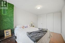 Bedroom featuring a decorative green wall panel, a built-in closet with sliding doors, a flush-mount ceiling light fixture, wood-finish flooring, and white painted walls - 