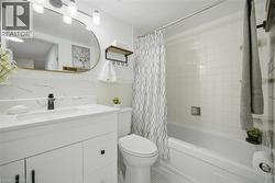 Bathroom featuring a white vanity with integrated sink, a tiled bathtub/shower combination, and mosaic tile flooring - 
