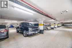 Subterranean parking garage featuring concrete flooring, overhead fluorescent lighting, and visible red utility pipes - 