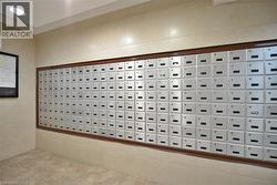 Wall-mounted mailboxes with a wood-finish frame, set against a tiled wall with recessed lighting - 