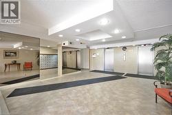Lobby area featuring tiled flooring, recessed lighting, mirrored walls, and multiple elevators with brushed metal doors - 