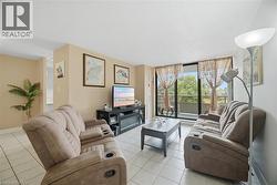 Living area featuring tile flooring, a built-in media console, and a glass-paneled sliding door leading to an outdoor balcony - 