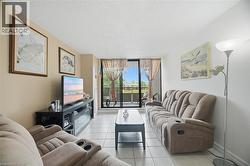 Living area featuring tile flooring, neutral wall tones, and a glass sliding door leading to an exterior balcony - 