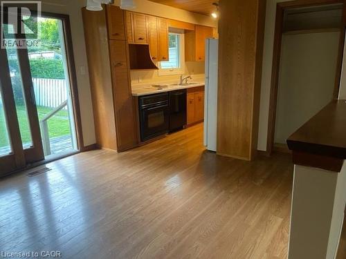 Kitchen featuring wood-finish flooring, light-toned cabinetry, light countertops, and a black oven - 48 Austin Drive Unit# Upper, Waterloo, ON - Indoor