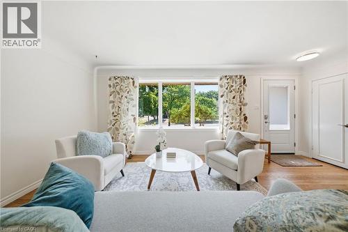 Bright living space featuring a large picture window, wood-finish flooring, and a white paneled door with a frosted glass insert - 80 Jackson Avenue, Kitchener, ON - Indoor Photo Showing Living Room