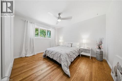 Bright room featuring wood-finish flooring, a contemporary ceiling fan with integrated lighting, a large window, and white trim throughout - 80 Jackson Avenue, Kitchener, ON - Indoor Photo Showing Bedroom