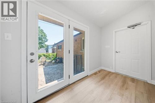 Double glass-paneled doors opening to an exterior patio with a stone-finish surface, complemented by light wood-finish flooring indoors - 80 Jackson Avenue, Kitchener, ON - Indoor Photo Showing Other Room