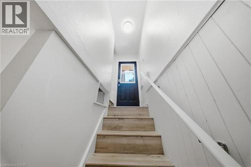 Staircase featuring wood-finish treads, a white handrail, and a dark entry door with window pane - 80 Jackson Avenue, Kitchener, ON - Indoor Photo Showing Other Room
