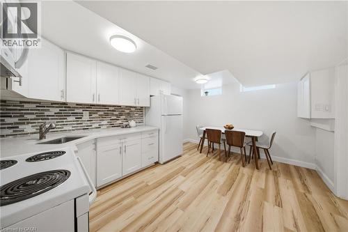 Modern kitchen featuring white shaker-style cabinetry, a mosaic tile backsplash, and light-toned wood-finish flooring - 80 Jackson Avenue, Kitchener, ON - Indoor