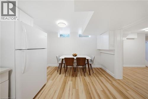 Open-concept kitchen area featuring light wood-finish flooring, white walls, recessed ceiling with contemporary flush mount lighting, and white cabinetry - 80 Jackson Avenue, Kitchener, ON - Indoor