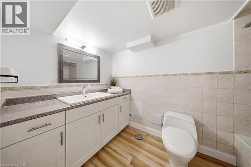 Bathroom featuring a white vanity with an integrated sink, a speckled countertop, and light wood-finish flooring - 80 Jackson Avenue, Kitchener, ON - Indoor Photo Showing Bathroom