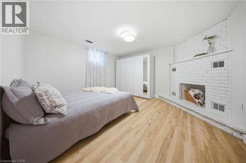 Bright living space featuring wood-finish flooring and a white painted brick fireplace - 80 Jackson Avenue, Kitchener, ON - Indoor Photo Showing Bedroom