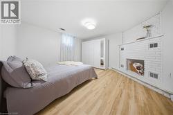 Bright living space featuring wood-finish flooring and a white painted brick fireplace - 