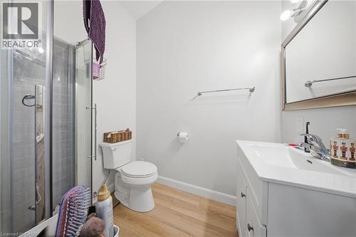 Bathroom featuring a glass-enclosed shower with subway tile, white vanity with integrated sink, wood-finish flooring, and a mirrored medicine cabinet with vanity lighting - 80 Jackson Avenue, Kitchener, ON - Indoor Photo Showing Bathroom
