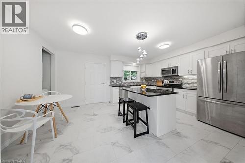 Bright kitchen featuring white cabinetry, stainless steel appliances, a black countertop island, and white marble-look floor tiles - 80 Jackson Avenue, Kitchener, ON - Indoor Photo Showing Kitchen With Upgraded Kitchen