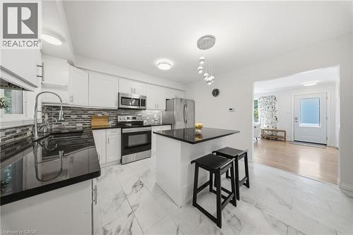 Kitchen featuring white cabinetry, black countertops, stainless steel appliances, and a mosaic tile backsplash - 80 Jackson Avenue, Kitchener, ON - Indoor Photo Showing Kitchen With Upgraded Kitchen