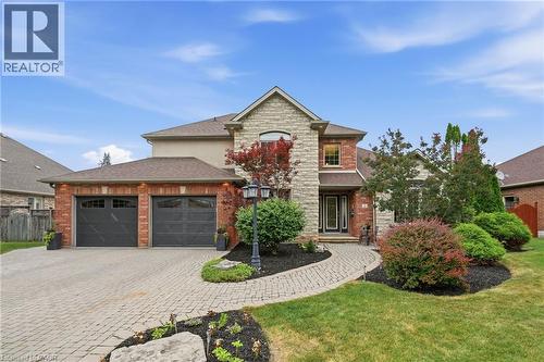 Brick and stone facade residence featuring a two-car garage with overhead lighting, a paver driveway, and a coordinating paver walkway - 5 Manor Crescent, Grimsby, ON - Outdoor