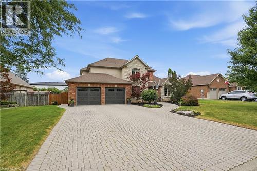 4 car Driveway. Exterior featuring a stone and brick facade, two-car garage with carriage-style doors, paver driveway, manicured landscaping, and mature foliage - 5 Manor Crescent, Grimsby, ON - Outdoor