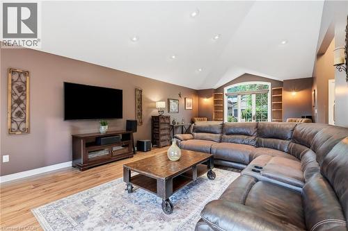 Vaulted ceiling living area featuring wood-finish flooring, a prominent arched window, recessed lighting, and built-in shelving - 5 Manor Crescent, Grimsby, ON - Indoor Photo Showing Living Room