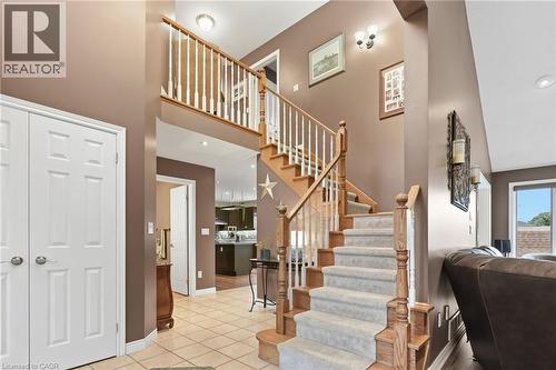 Two-story foyer featuring a staircase with wood-finish handrails and carpeted treads, tile flooring, and white paneled doors - 5 Manor Crescent, Grimsby, ON - Indoor Photo Showing Other Room