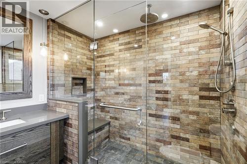 Walk-in shower with clear glass enclosure, natural stone tile walls, a built-in shower bench, and recessed niche - 5 Manor Crescent, Grimsby, ON - Indoor