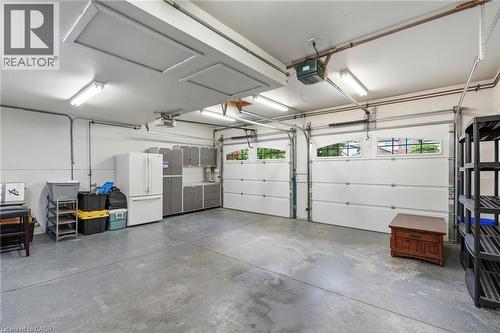 Spacious two-car garage featuring a concrete floor, two white garage doors with upper windows, and fluorescent overhead lighting - 5 Manor Crescent, Grimsby, ON - Indoor Photo Showing Garage