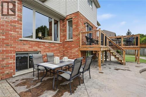 Multi-level wooden deck with black balusters, brick exterior, and a lower-level concrete patio - 5 Manor Crescent, Grimsby, ON - Outdoor With Deck Patio Veranda With Exterior